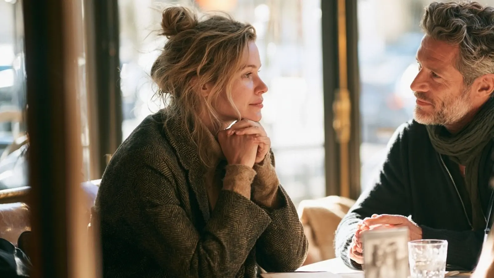 Deux adultes échangent calmement face à face dans un café lumineux